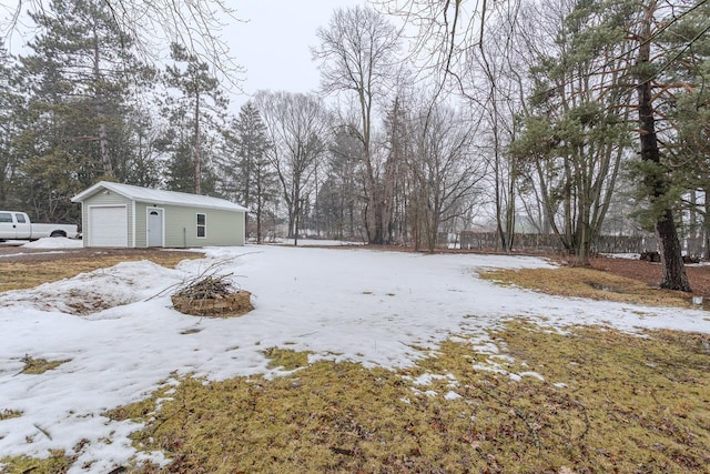 yard layered in snow featuring a garage and an outdoor structure