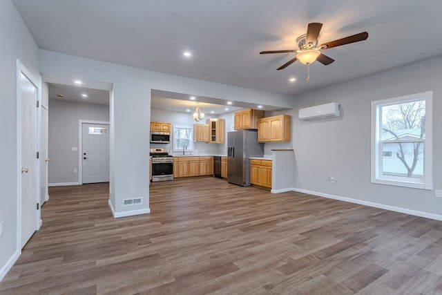 kitchen featuring appliances with stainless steel finishes, a wall mounted AC, visible vents, and baseboards