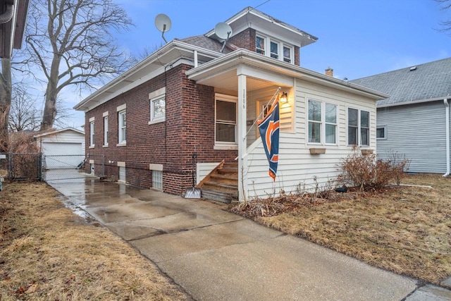 view of front of home with a garage, brick siding, and an outdoor structure