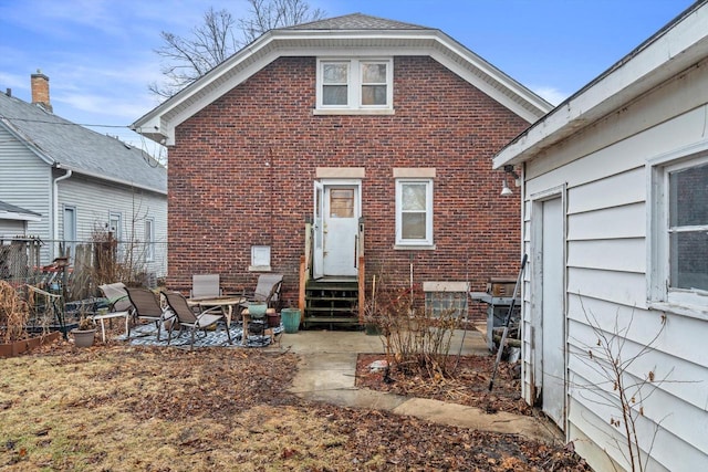 rear view of property with entry steps, a patio area, and brick siding