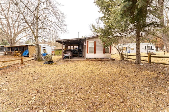 back of property with fence and a carport