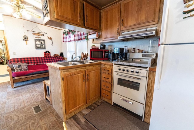 kitchen featuring white appliances, ventilation hood, a sink, and brown cabinets