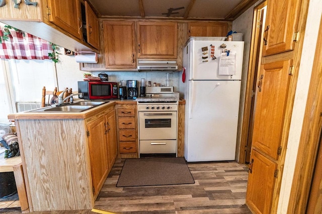 kitchen featuring range hood, brown cabinets, light countertops, wood finished floors, and white appliances