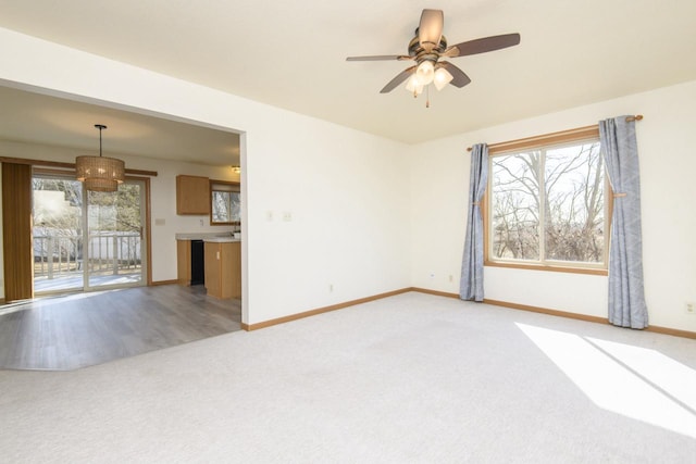 unfurnished living room with baseboards, light carpet, and ceiling fan