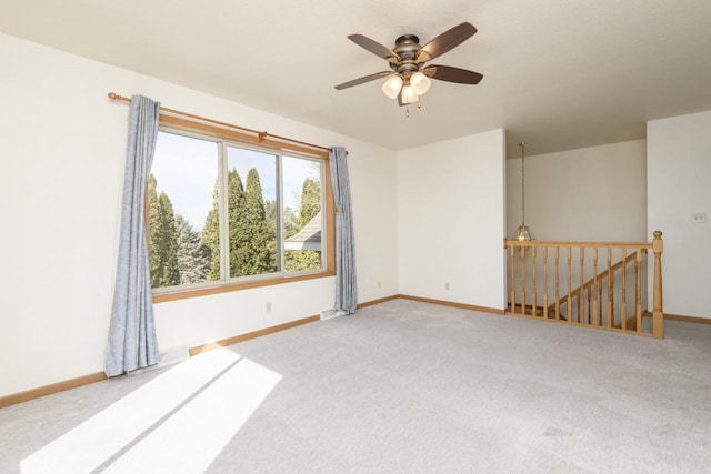 carpeted spare room featuring a ceiling fan and baseboards