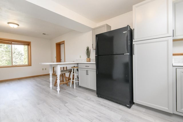 kitchen featuring baseboards, visible vents, freestanding refrigerator, light countertops, and light wood-style floors