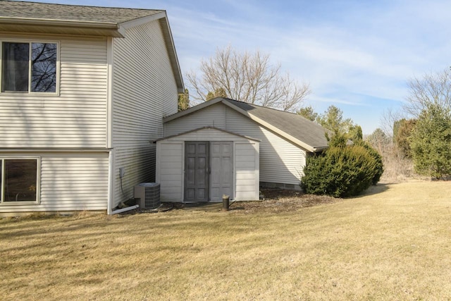 view of property exterior featuring an outbuilding, cooling unit, roof with shingles, a storage shed, and a lawn