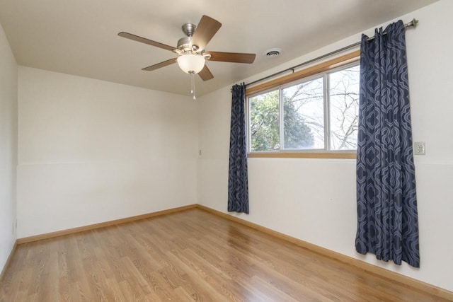 unfurnished room with visible vents, baseboards, wood finished floors, and a ceiling fan