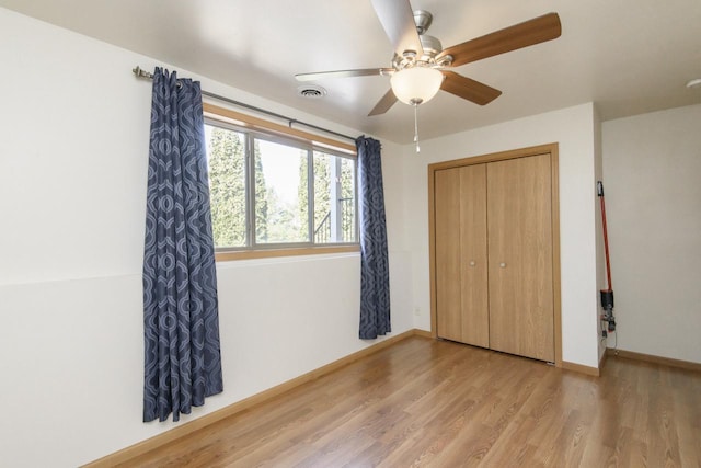 unfurnished bedroom with visible vents, a ceiling fan, wood finished floors, a closet, and baseboards