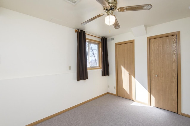 unfurnished bedroom featuring carpet flooring, ceiling fan, baseboards, and visible vents