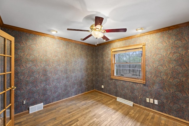 spare room with visible vents, crown molding, and wood-type flooring