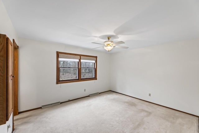 spare room with light carpet, visible vents, baseboards, and a ceiling fan