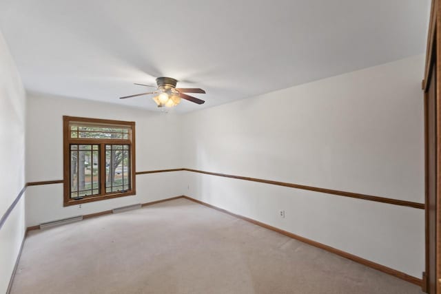 spare room featuring a ceiling fan, visible vents, light colored carpet, and baseboards