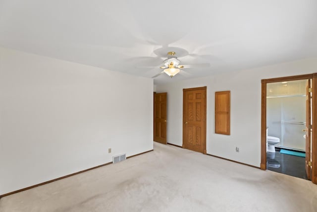 unfurnished bedroom featuring baseboards, visible vents, ceiling fan, ensuite bathroom, and light carpet