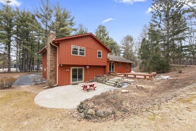 rear view of property featuring a wooden deck, a patio, and a chimney