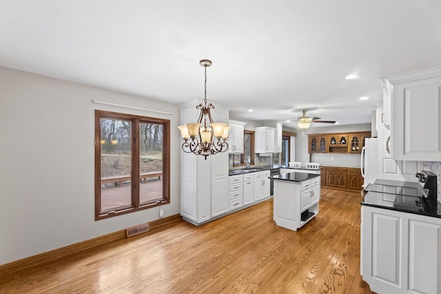 kitchen with dark countertops, visible vents, light wood-style floors, white cabinetry, and a sink