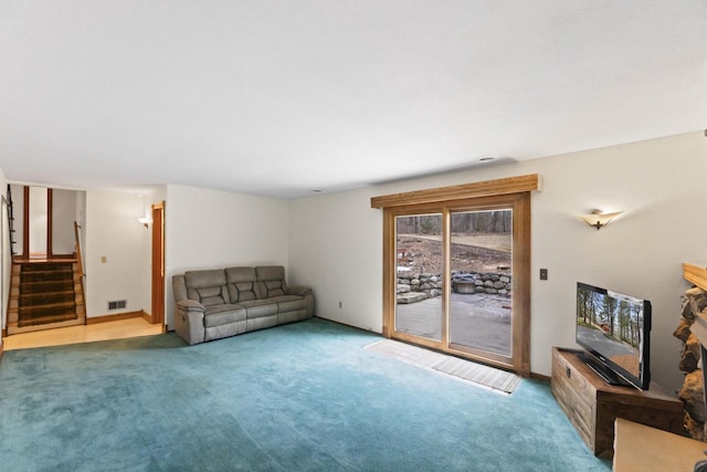 carpeted living room featuring visible vents, baseboards, and stairway