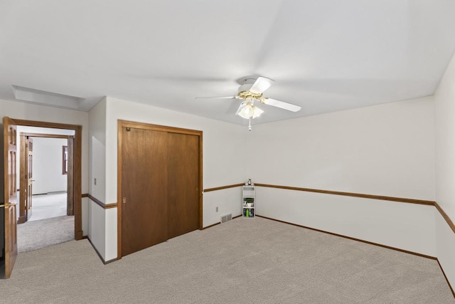 unfurnished bedroom with a ceiling fan, light colored carpet, visible vents, and a closet