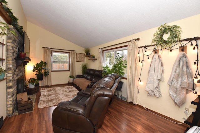 living area featuring vaulted ceiling, a textured ceiling, a fireplace, and wood finished floors