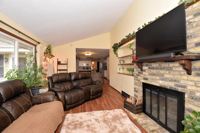 living room with lofted ceiling, a textured ceiling, a fireplace, and wood finished floors