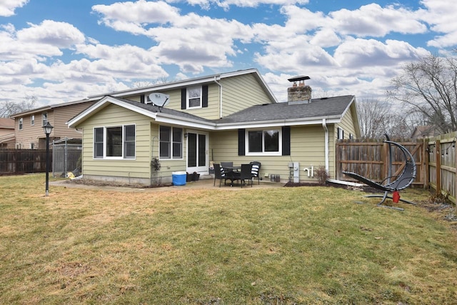 back of house with a chimney, a lawn, a patio area, and a fenced backyard