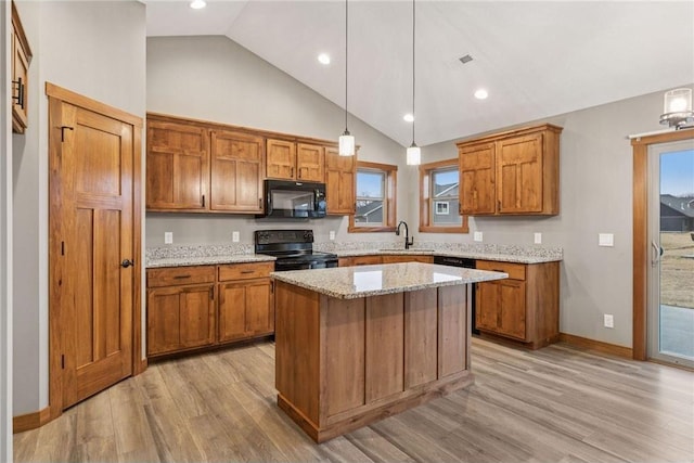 kitchen with black appliances, light wood-style flooring, brown cabinets, and a sink