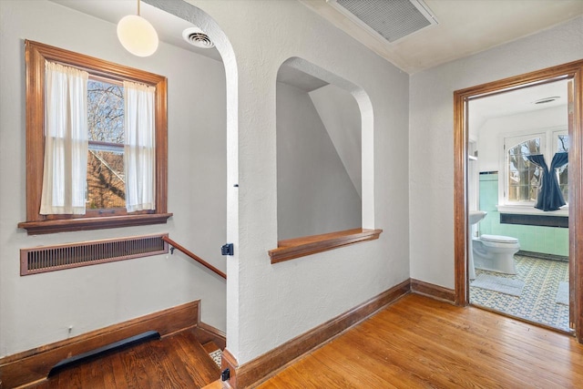 hallway featuring visible vents, baseboards, and wood finished floors