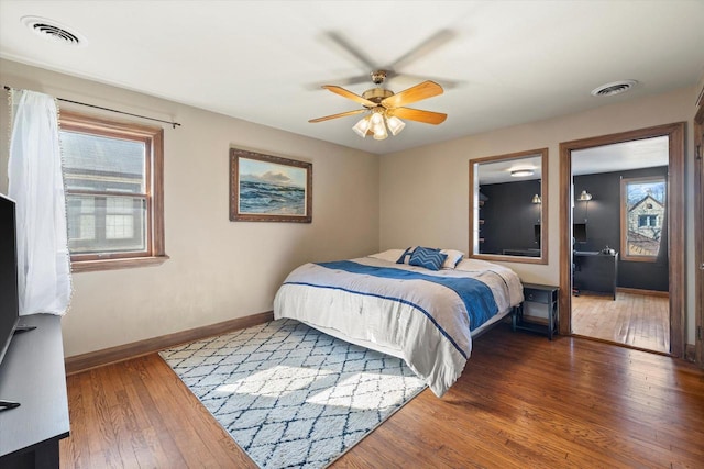 bedroom featuring a ceiling fan, visible vents, baseboards, and hardwood / wood-style flooring