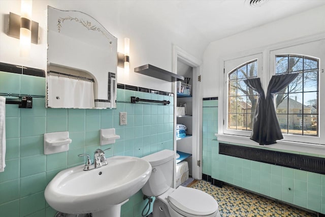 full bath with a sink, tile walls, and toilet