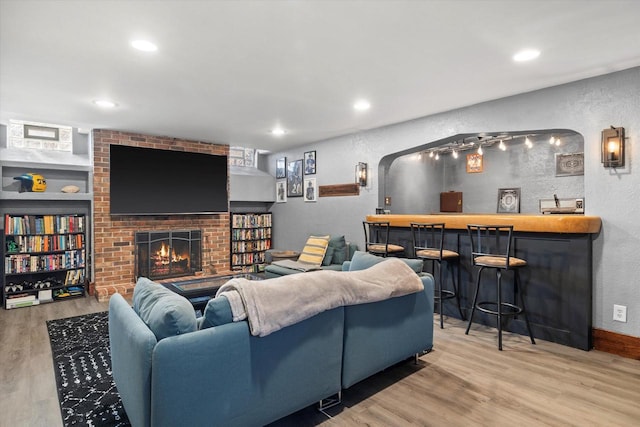 living room featuring a bar, a fireplace, wood finished floors, and a textured wall