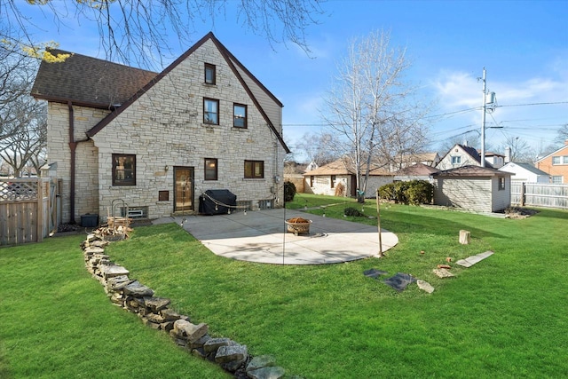 rear view of house with a patio, an outdoor fire pit, a fenced backyard, a shingled roof, and a yard