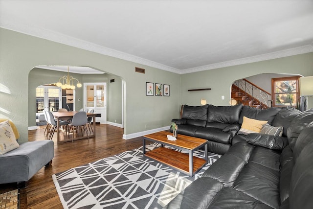 living room with baseboards, crown molding, arched walkways, and wood finished floors