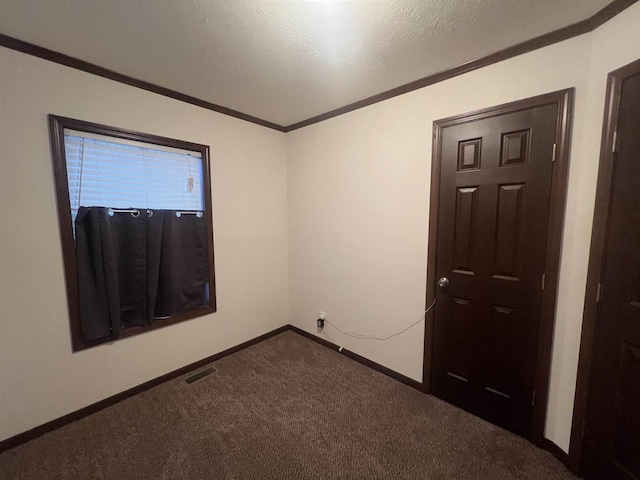 carpeted spare room with visible vents, crown molding, a textured ceiling, and baseboards