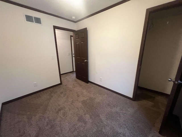 unfurnished bedroom with ornamental molding, carpet, visible vents, and baseboards