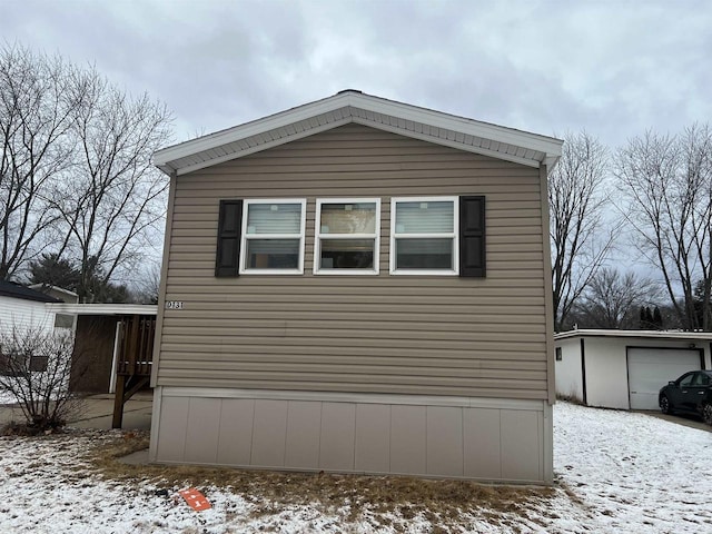 snow covered property featuring a garage and an outbuilding