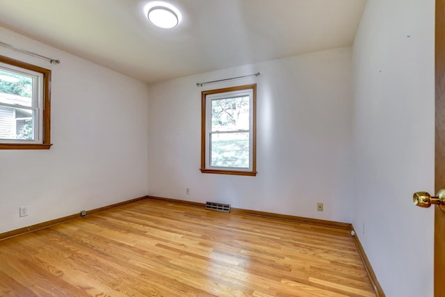 empty room featuring visible vents, light wood-style flooring, and baseboards