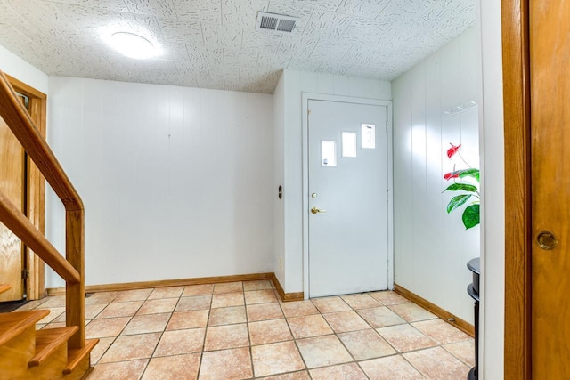 entryway with light tile patterned floors, baseboards, stairs, and visible vents