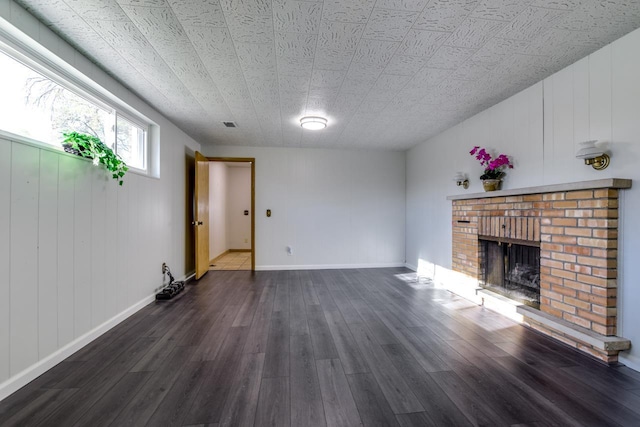 unfurnished living room with a fireplace, baseboards, and wood finished floors