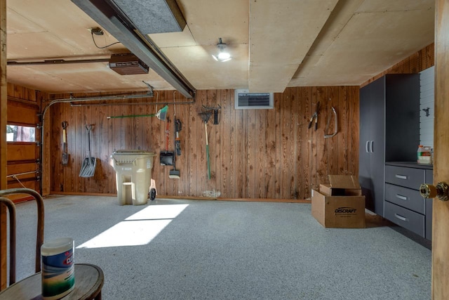 below grade area with a garage, carpet floors, wooden walls, and visible vents