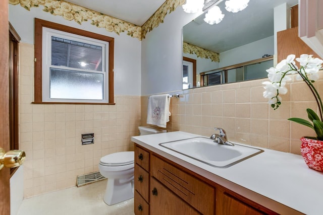 full bath with a wainscoted wall, tile walls, visible vents, toilet, and an enclosed shower