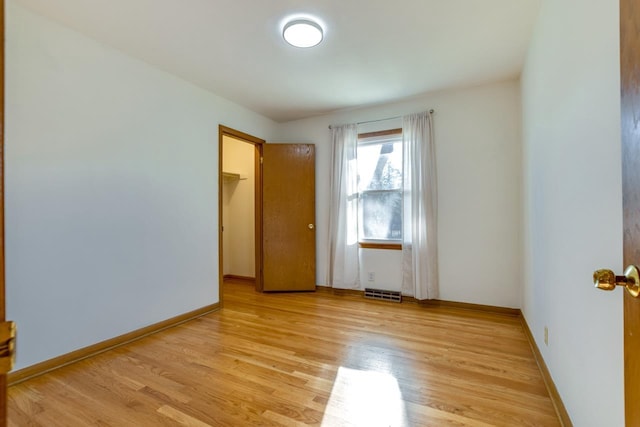 unfurnished room with light wood finished floors, visible vents, and baseboards