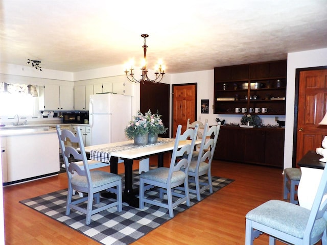 dining room with light wood-style floors and a notable chandelier