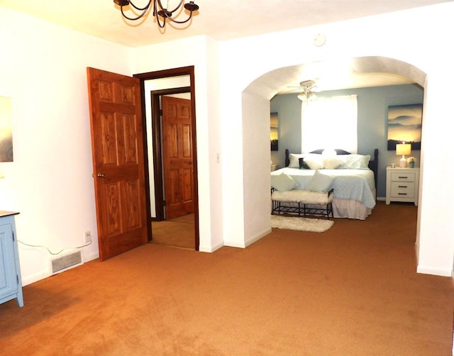 carpeted bedroom featuring baseboards, visible vents, arched walkways, and a notable chandelier