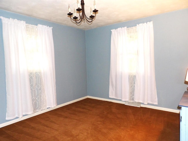 spare room featuring baseboards and a chandelier