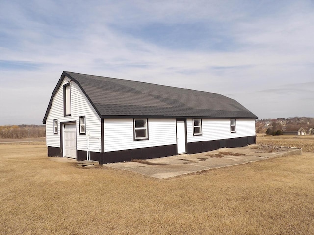 view of front of home featuring a shingled roof, a front yard, and a detached garage