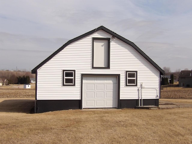 view of side of home featuring a garage, a yard, an outbuilding, and a gambrel roof