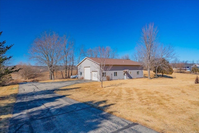 view of side of property with a yard, driveway, and a garage