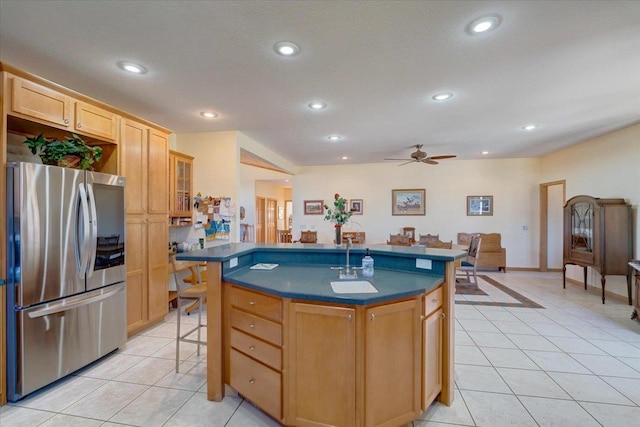 kitchen featuring a sink, dark countertops, freestanding refrigerator, recessed lighting, and light tile patterned floors