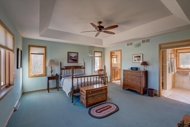 carpeted bedroom featuring visible vents, a raised ceiling, and multiple windows