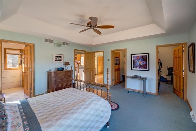 bedroom with visible vents, baseboards, a walk in closet, and a tray ceiling